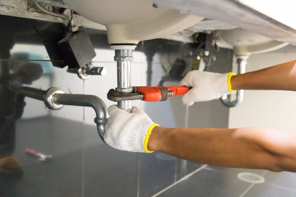 Plumber,Fixing,White,Sink,Pipe,With,Adjustable,Wrench. Plombier à Sainte-Cécile-les-Vignes